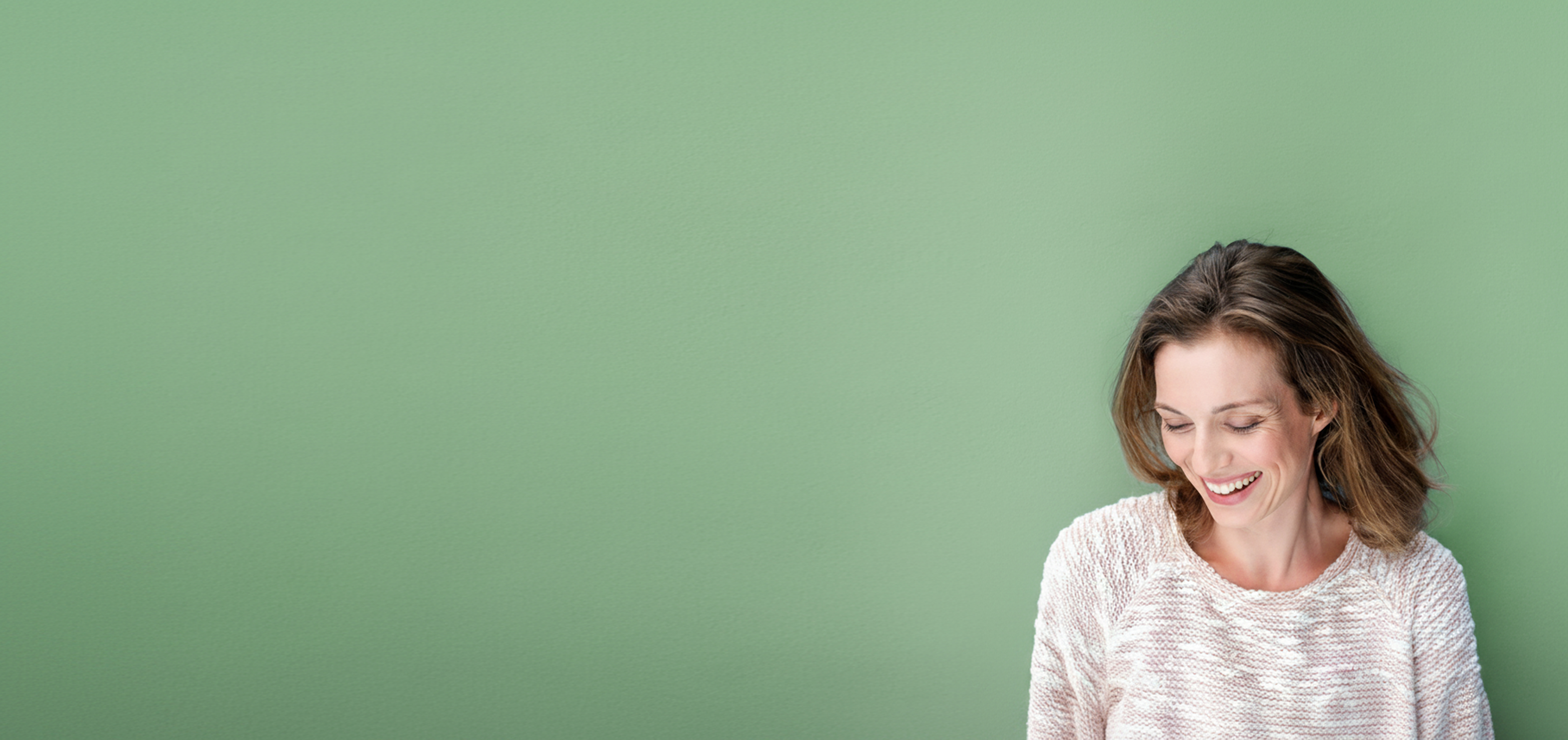 Smiling patient against a sage-green wall